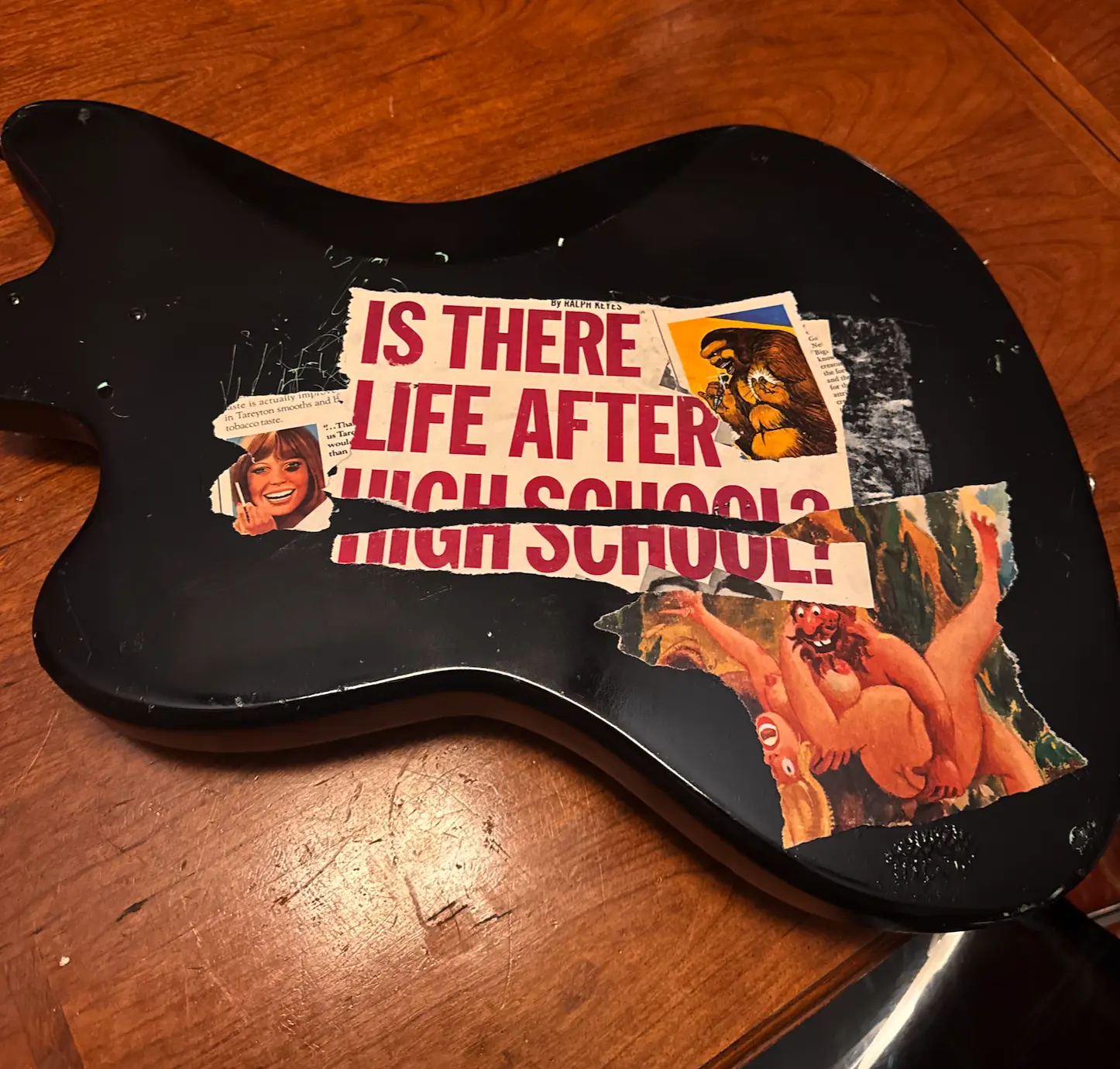 Back of the black guitar covered with torn vintage collage art