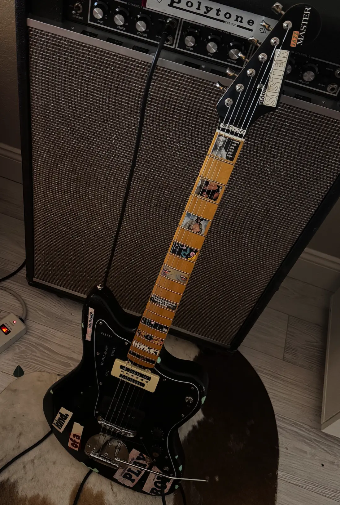 Finished black collage-covered guitar leaning against a vintage amplifier